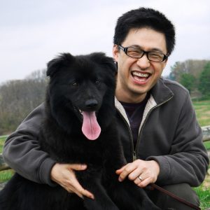 Man Smiling and Holding Happy Black Dog